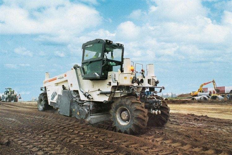 A large white tractor is on the dirt.