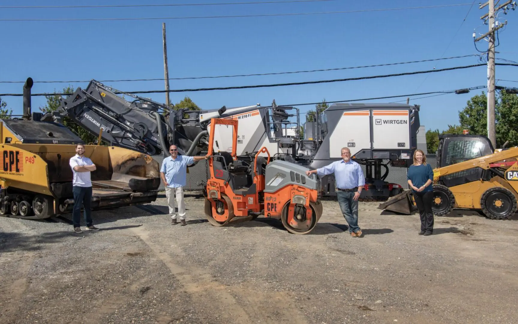 Three men standing next to a small construction vehicle.